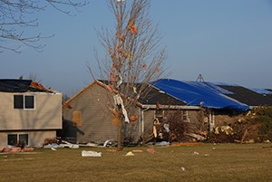 PIcture of a blue tarp on a roof that is damaged